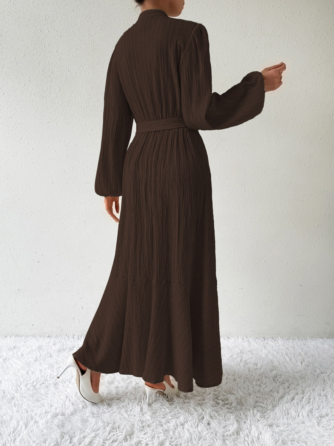 Back view of the Honey Tie Waist Long Sleeve Dress in a dark brown shade. Features a flowing maxi length, tie waist, and textured fabric.